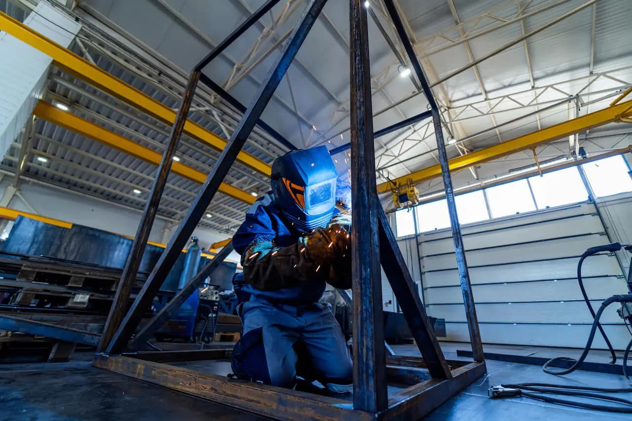Soldador trabajando en fabricación de estructura metálica
