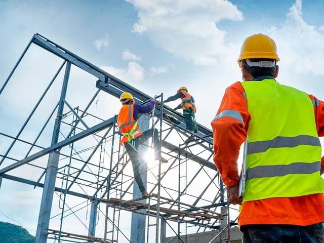 Trabajadores en andamio montando estructura metálica